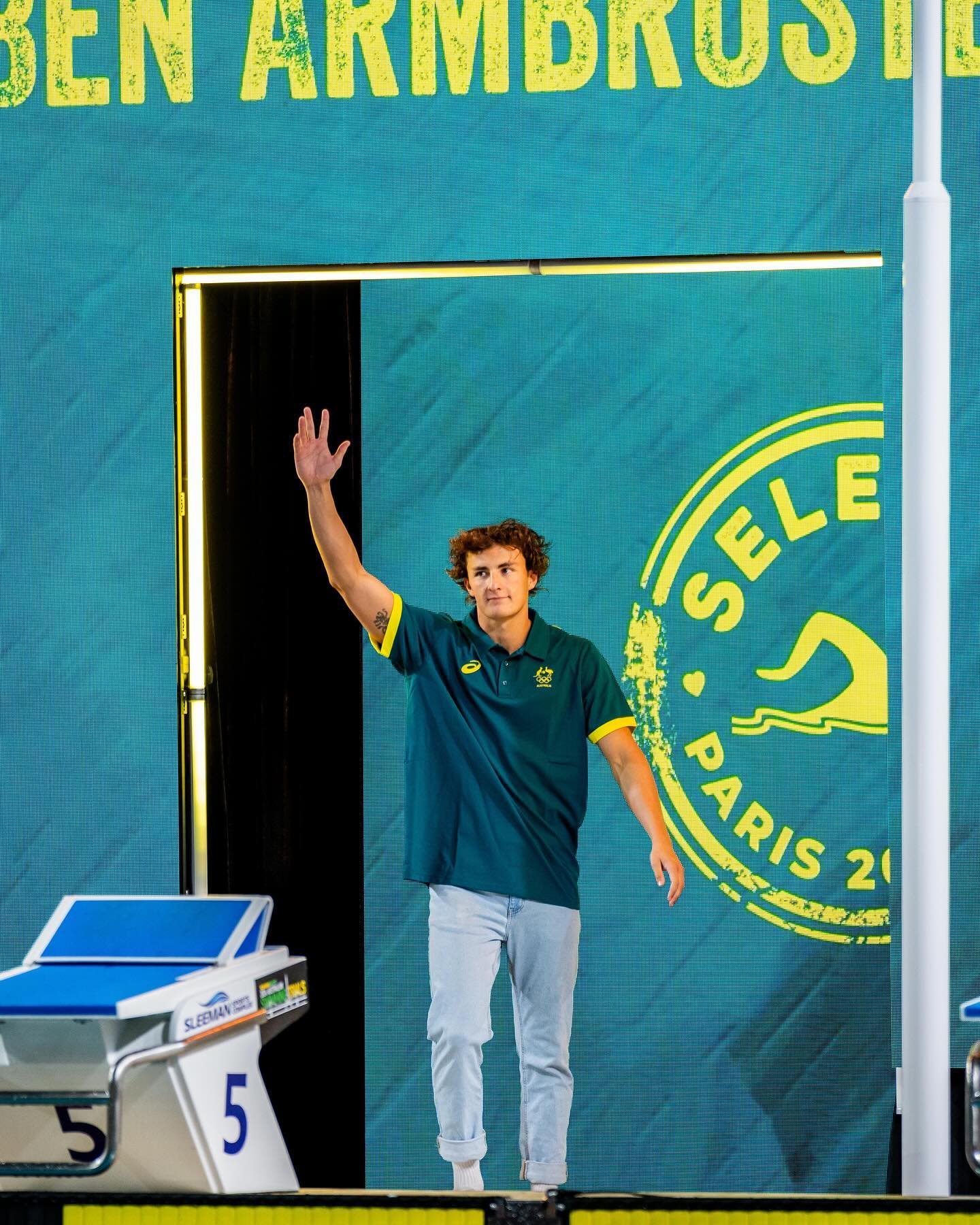 Olympic swimmer Ben Armbruster is raising his hand to wave. 