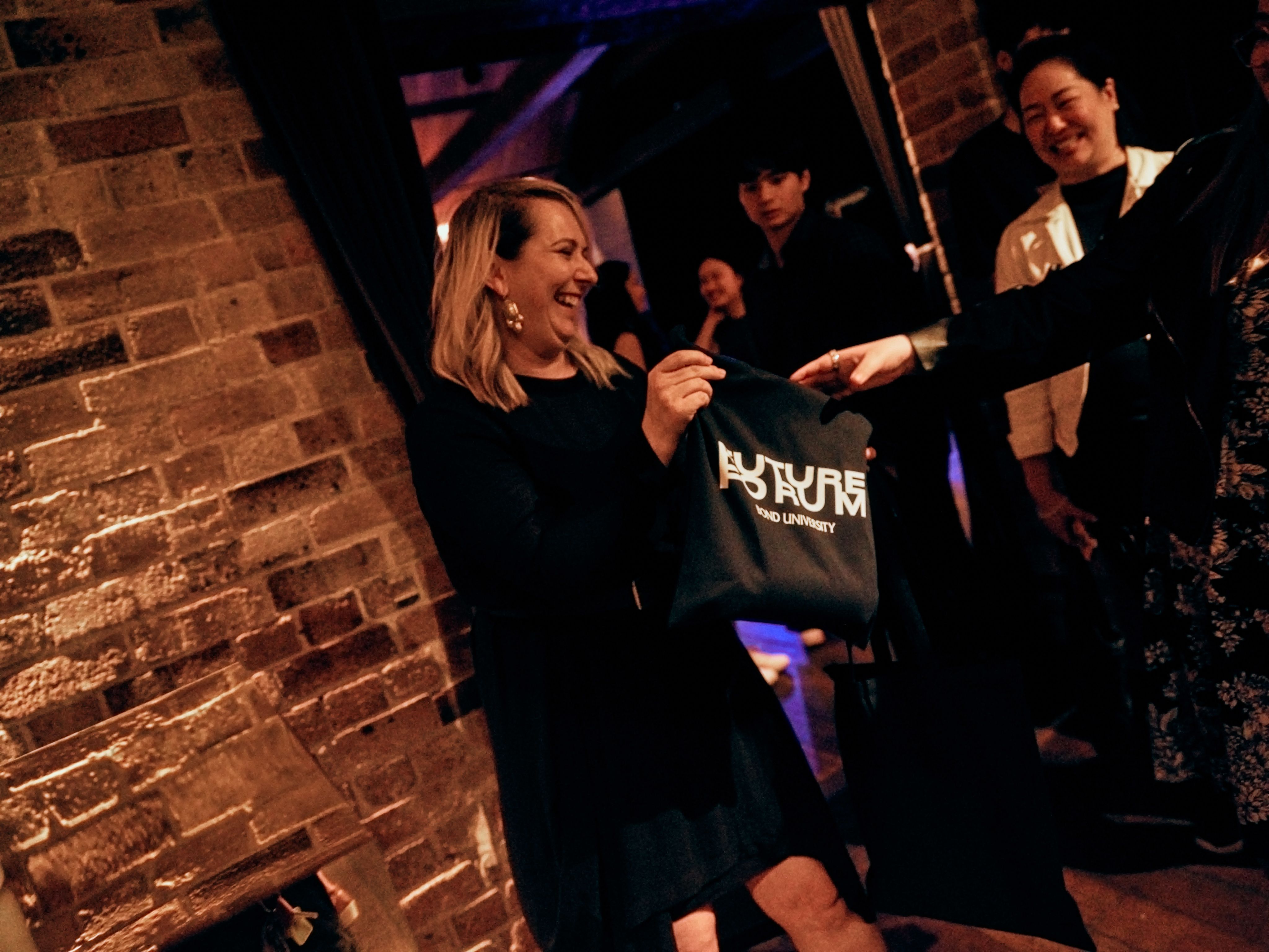 A woman is smiling as she hands a bag to a person. 