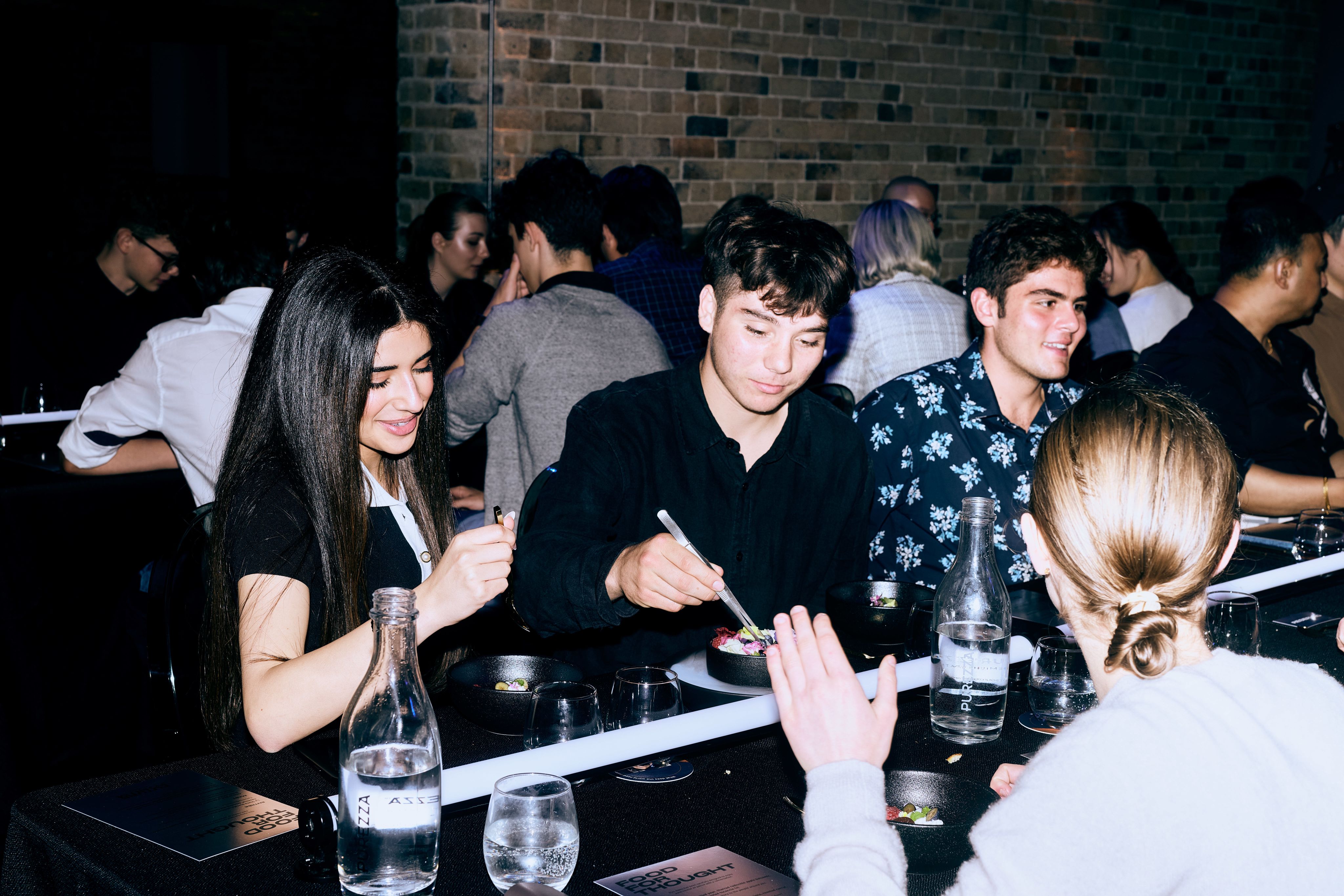 Young adults are eating at a table.