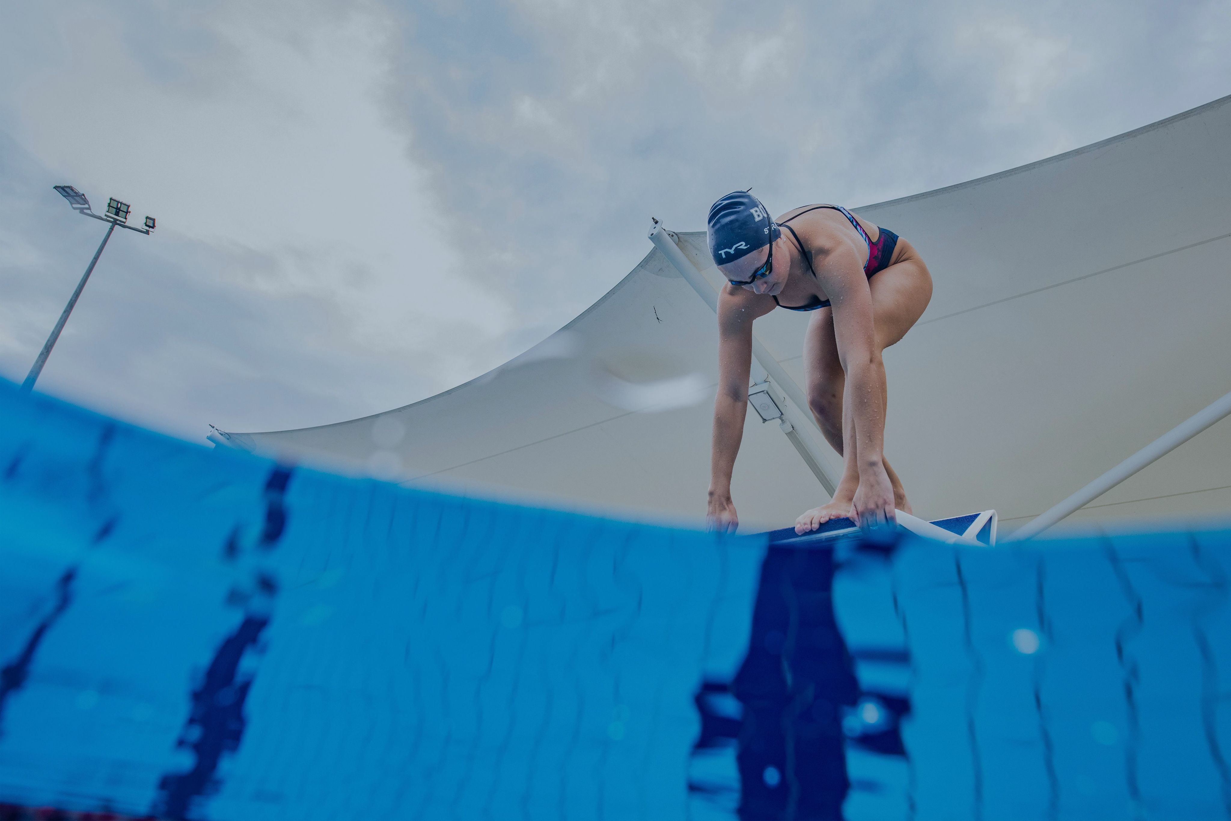 A swimmer is poised to dive off a block. 