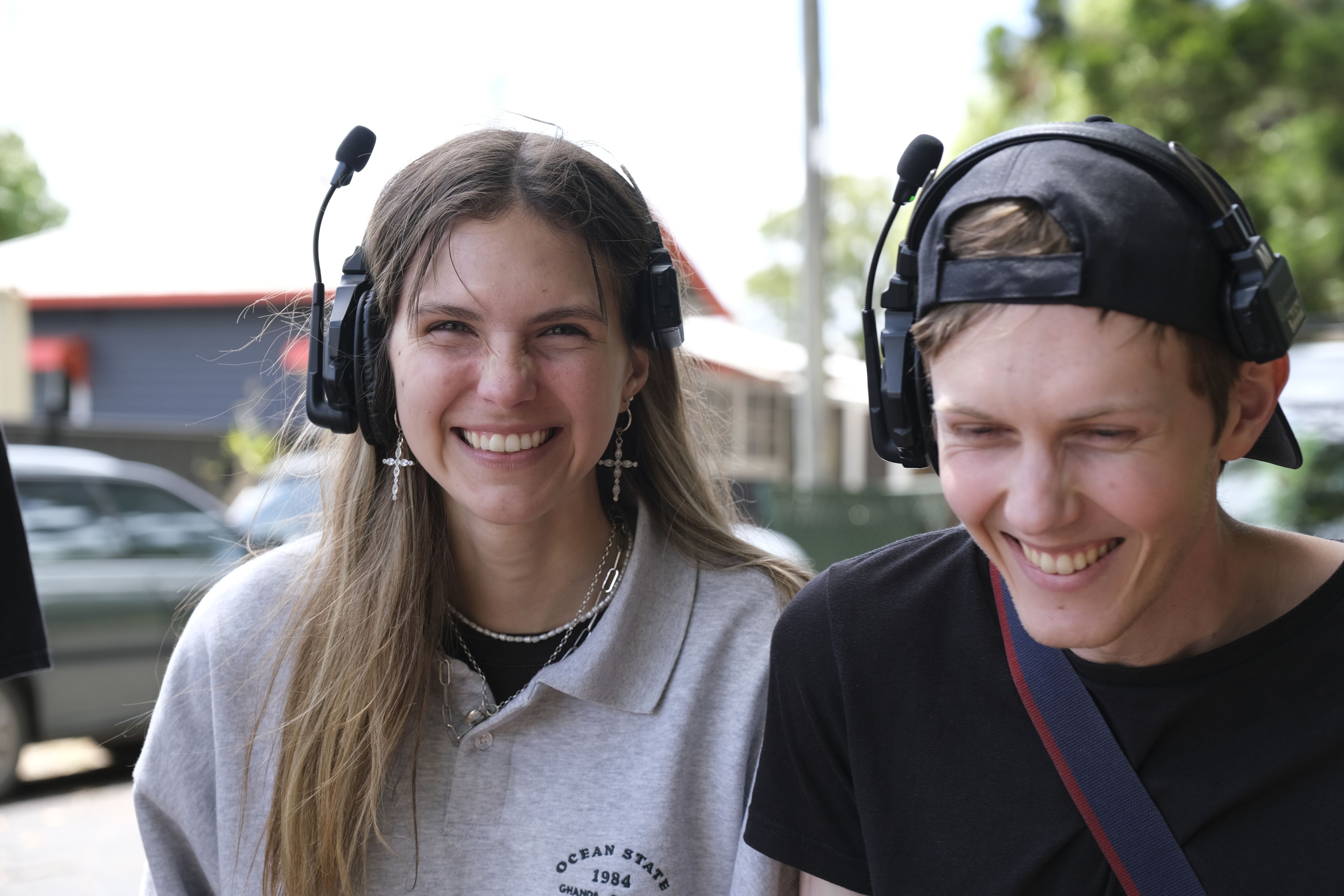 A female and male student wearing headsets smile to camera