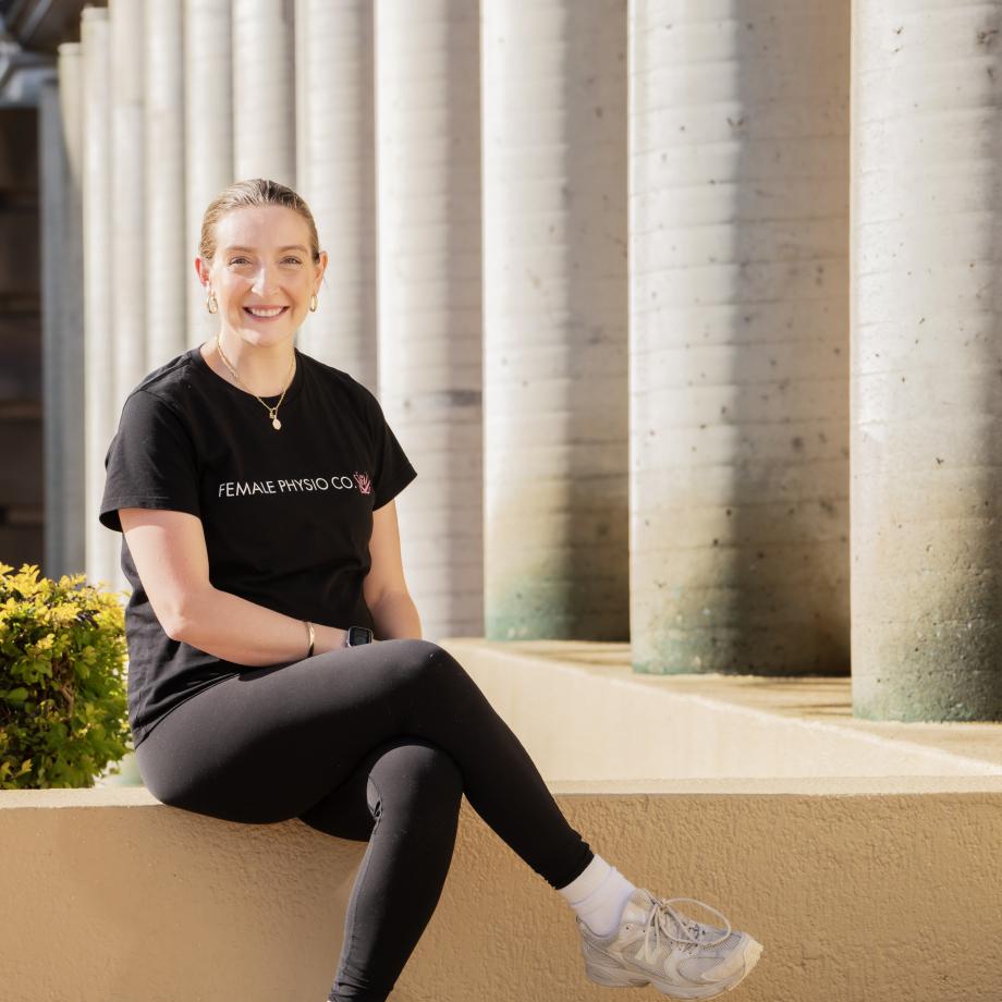 a woman with her legs crossed in front of sandstone pillars