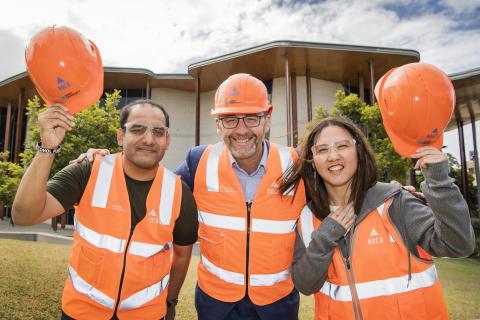 three people wearing orange hardhats and hi-vis safety gear 
