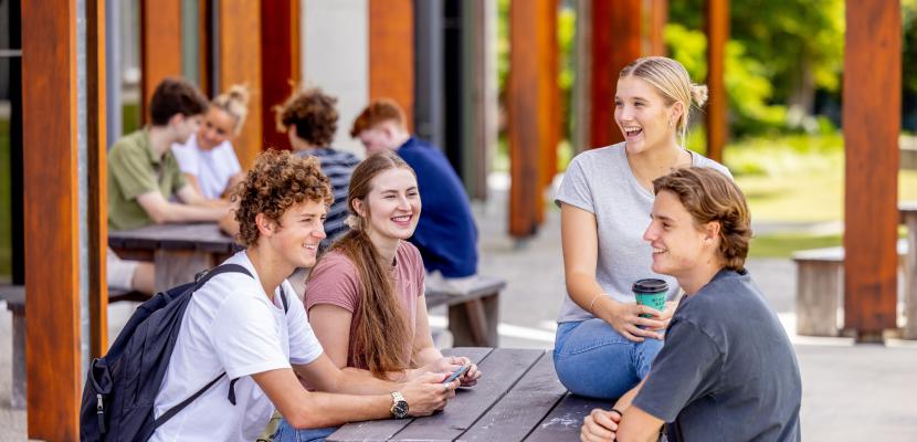 Four students socialising on a bench at Abedian school of Architecture.