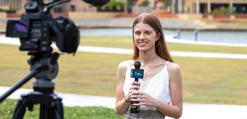 Jessica Borten holding a microphone, speaking to a camera at Bond University.