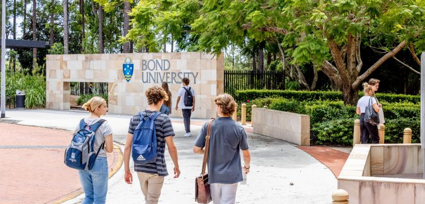 Students walking into Bond Unviersity from the top roundabout entrance on a sunny day
