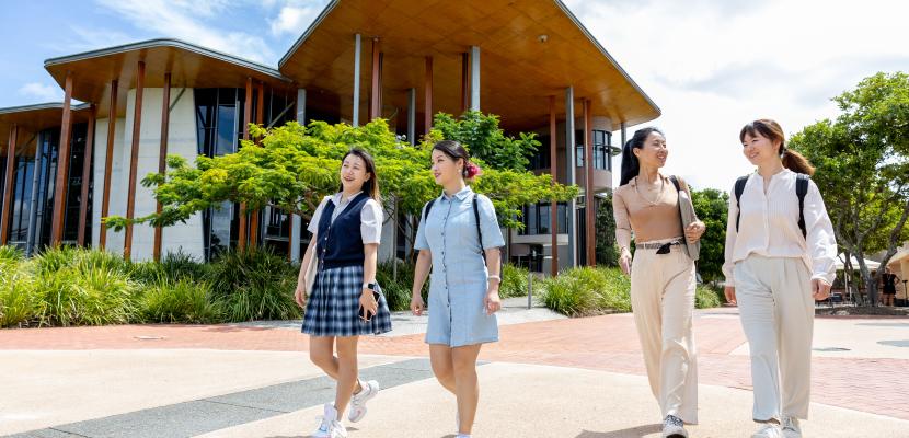 Four female students walking past the Abedian School of Architecture building on a sunny day