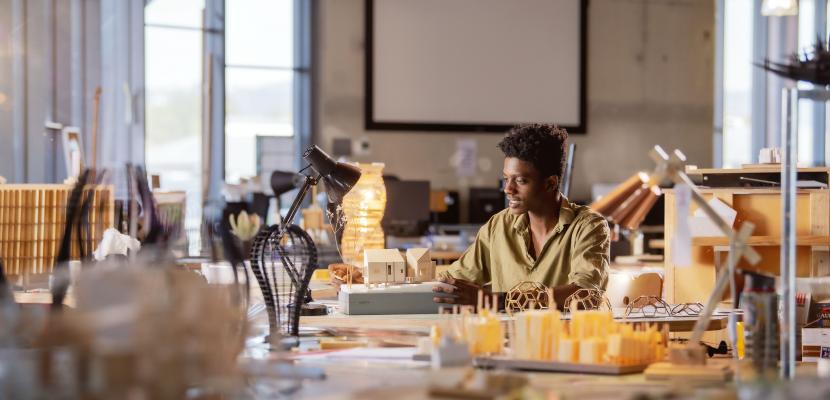 Chisomo Banzi, Architect alumnus, sitting at his desk completing a project
