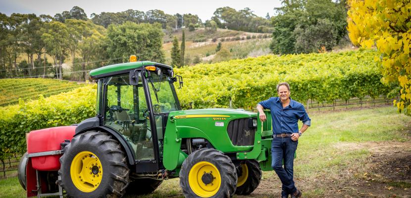 Alumus Antony Elsby leaning on a green tractor in a field 