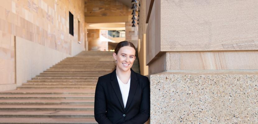 Ella Warrall, a white woman with brown hair, stands on the Bond University Thinking Steps and smiles