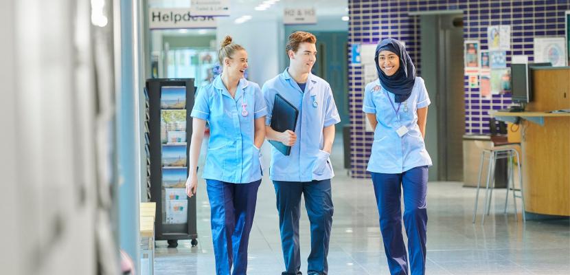 A group of medical students are smiling as they walk through a hospital 