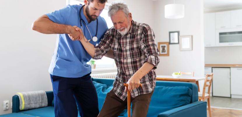 A doctor helps an elderly man to stand up from a chair