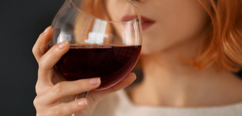 Person drinking a glass of red wine