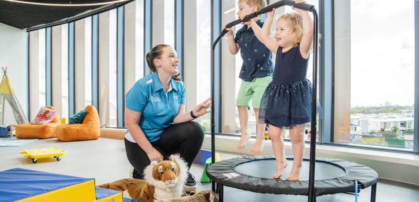 two kids bouncing on trampoline whilst being assessed by a allied health professional