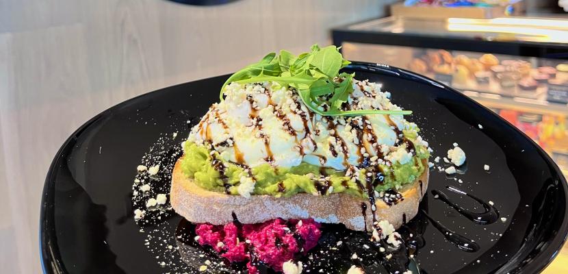 An avocado toast breakfast pictured in front of a sign that reads "Panacea". 