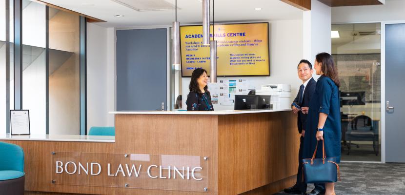 A man and a woman talk with the receptionist at the Bond Law Clinic