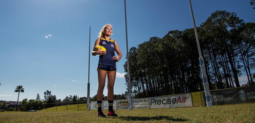 Women's AFL player standing for a photo on a sunny day. 