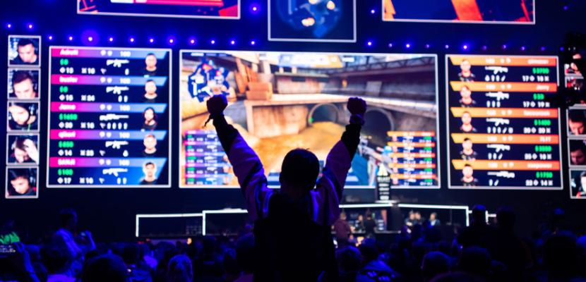 A person is cheering on a screen playing esports. 