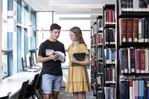 Two people standing inside the Faculty of Law Library.