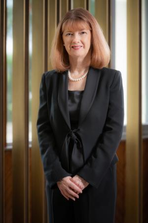Dr Jennifer Cronin standing in a black suit, smiling
