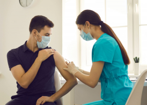 A person receives a needle in their arm from a medical person