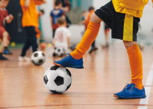 Child has their foot balancing on top of a soccer ball 