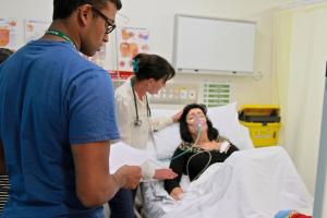 Doctor and student doctor check on patient in hospital bed
