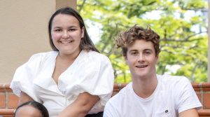 Two students sit smiling at the camera