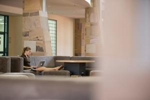 A student sits in the distance on her laptop